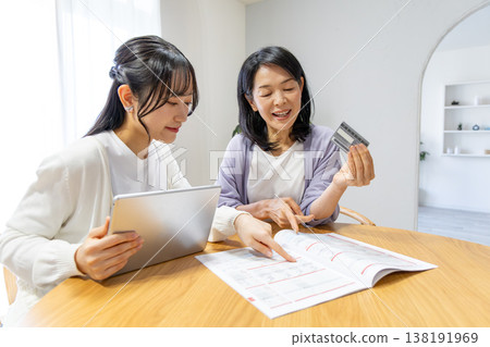 一對母女正在網路上瀏覽商品目錄。 138191969
