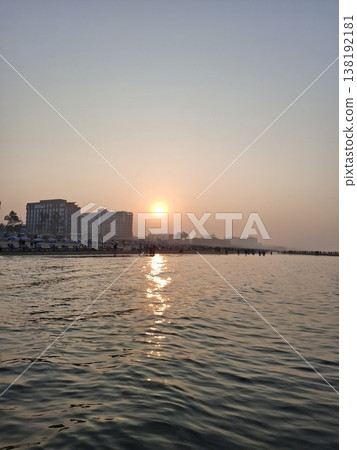 Golden Sunset Over Coastal City Skyline With Calm Water and Reflective Sunlight at Dusk Golden Sunset Over Coastal City Skyline With Calm Water and Reflective Sunlight at Dusk 138192181