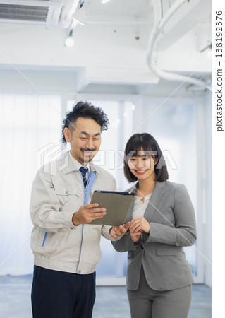 A businesswoman and a worker with dissatisfied expressions looking at the air conditioner 138192376