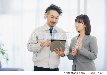 A businesswoman and a worker with dissatisfied expressions looking at the air conditioner A businesswoman and a worker with dissatisfied expressions looking at the air conditioner 138192378