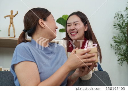 Mother and daughter sharing a joyful moment with a gift Mother and daughter sharing a joyful moment with a gift 138192403