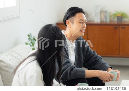 一對情侶坐在沙發上看著他們的智慧型手機 一對情侶坐在沙發上看著他們的智慧型手機 138192486