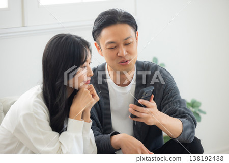 一對情侶坐在沙發上看著他們的智慧型手機 138192488