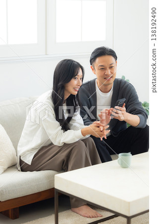 一對情侶坐在沙發上看著他們的智慧型手機 138192490