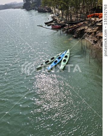 Three Colorful Kayaks Floating Near a Rocky Shoreline on Calm Green Water for Outdoor Adventure Three Colorful Kayaks Floating Near a Rocky Shoreline on Calm Green Water for Outdoor Adventure 138192768