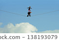 Woman balancing on rope supported by partner against blue sky background. 138193079
