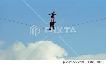 Woman balancing on rope supported by partner against blue sky background. 138193079