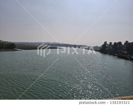 Calm River Landscape With Distant Shoreline, Hazy Sky and Sparkling Water Reflections on a Sunny Day Calm River Landscape With Distant Shoreline, Hazy Sky and Sparkling Water Reflections on a Sunny Day 138193321