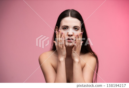 Woman applying a rejuvenating sheet mask to her face, a skincare essential for hydration and healthy skin, promoting beauty and wellness with delicate facial care Woman applying a rejuvenating sheet mask to her face, a skincare essential for hydration and healthy skin, promoting beauty and wellness with delicate facial care 138194217