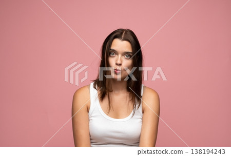 Woman making duck face expression, showing playful mood and positive emotions on pink background Woman making duck face expression, showing playful mood and positive emotions on pink background 138194243