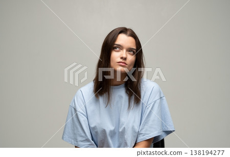 Young woman looking up, thinking, contemplating, or feeling bored, isolated on a neutral gray background Young woman looking up, thinking, contemplating, or feeling bored, isolated on a neutral gray background 138194277