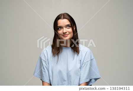 Young woman smiling while looking up and away, thinking about ideas, future, and aspirations 138194311