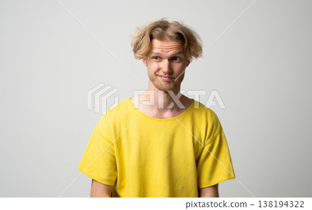 Young man wearing a yellow t-shirt looking sideways with a questioning expression, feeling skeptical and uncertain while thinking with doubt and curiosity Young man wearing a yellow t-shirt looking sideways with a questioning expression, feeling skeptical and uncertain while thinking with doubt and curiosity 138194322