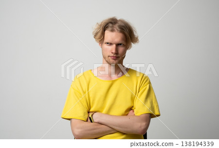 Young man showing distrustful and suspicious expression, raising eyebrow, feeling skeptical, doubting, questioning, and having arms crossed in studio portrait with negative emotions 138194339