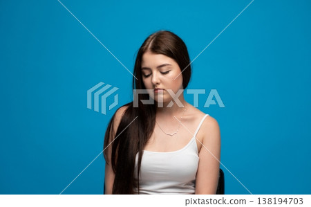 Young woman experiencing sadness and melancholy, bowing head down in emotional distress or depression 138194703