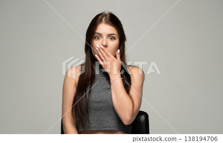 Woman gasping in surprise, covering mouth with hand, reacting with disbelief and wide-eyed shock Woman gasping in surprise, covering mouth with hand, reacting with disbelief and wide-eyed shock 138194706