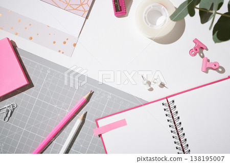 Top view of pink stationery, open notebook, and craft supplies on a grey mat. Copy space. Top view of pink stationery, open notebook, and craft supplies on a grey mat. Copy space. 138195007
