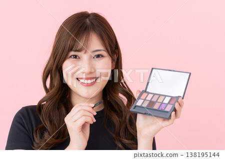一位年輕女子拿著眼影盤 一位年輕女子拿著眼影盤 138195144