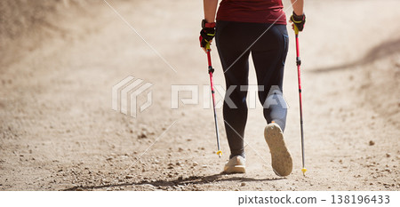 Senior woman walking in forest with Nordic walking sticks, sunny summer day. An active lifestyle in retirement, a hike in nature 138196433