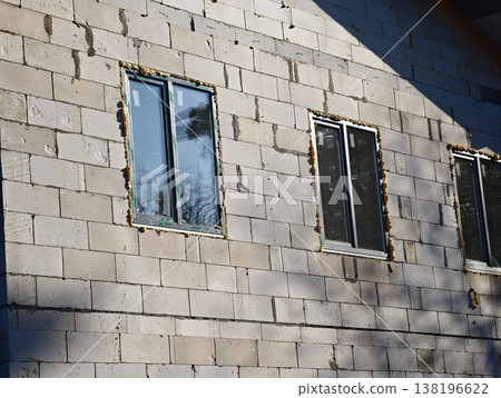 Construction site shows unfinished wall with double-glazed windows in clear daylight hours Construction site shows unfinished wall with double-glazed windows in clear daylight hours 138196622