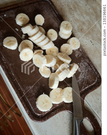 Slicing bananas on a wooden cutting board in a kitchen setting 138196661