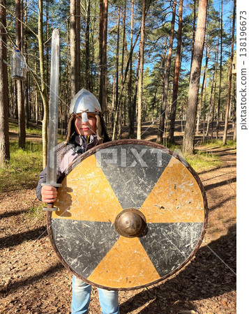 Person holds a sword and shield while standing in a forest during daytime Person holds a sword and shield while standing in a forest during daytime 138196673
