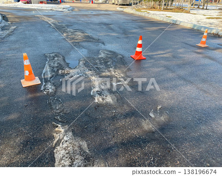 Cold weather causes icy patches on parking lot with cones for safety 138196674