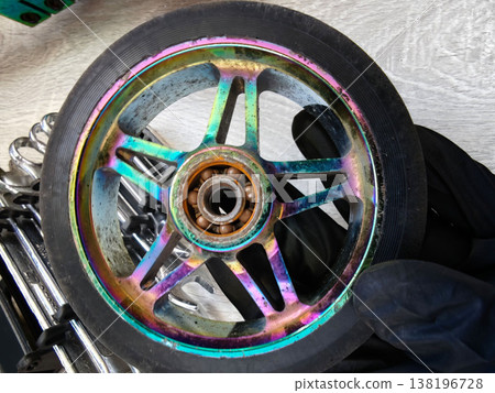 Colorful scooter wheel shows wear and tear while being held in a hand Colorful scooter wheel shows wear and tear while being held in a hand 138196728