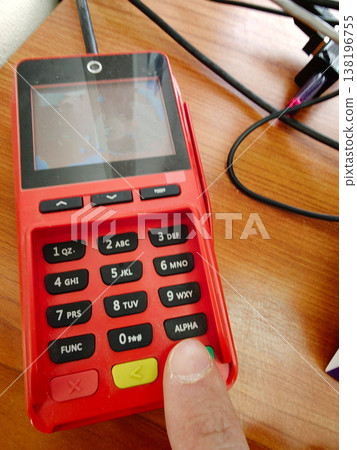 Red keypad device on wooden surface while a finger presses the button Red keypad device on wooden surface while a finger presses the button 138196755
