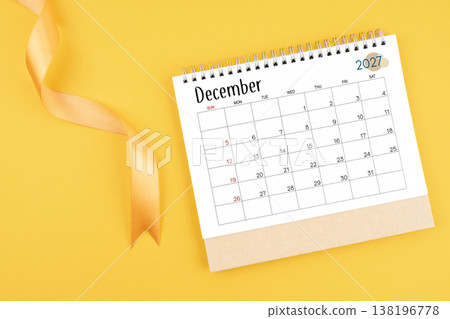 December 2027 desk calendar with yellow ribbon on yellow color background. 138196778