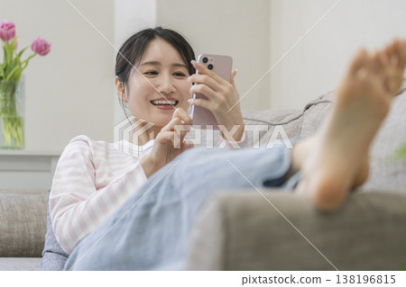 坐長沙發和操作智能手機的一個少婦 坐長沙發和操作智能手機的一個少婦 138196815