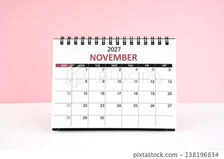 November 2027 desk calendar on white table with pink background. 138196834