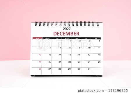 December 2027 desk calendar on white table with pink background. December 2027 desk calendar on white table with pink background. 138196835