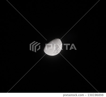 First Quarter Moon shines brightly in the dark night sky, revealing its textured surface and numerous craters 138196898