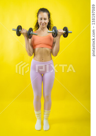 Woman exercising with dumbbells, training biceps for strength 138197089