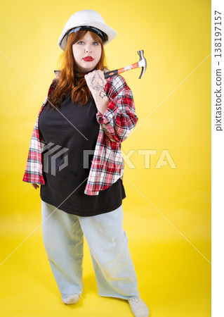 Woman wearing hard hat holding hammer ready for work Woman wearing hard hat holding hammer ready for work 138197157