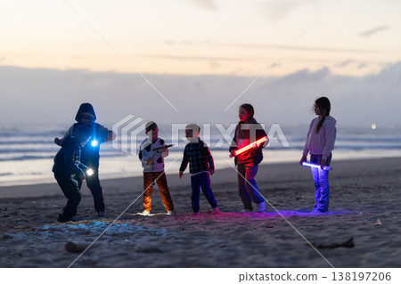 Children playing with lights on beach at sunset Children playing with lights on beach at sunset 138197206
