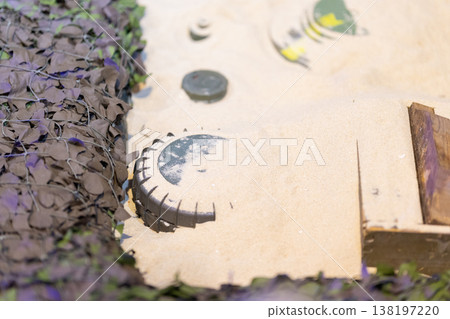 Land mine partially buried in sandy ground 138197220