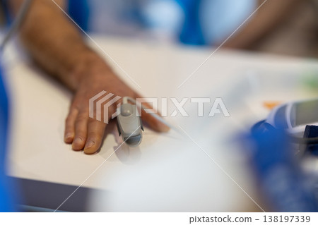Patient hand with pulse oximeter monitoring vital signs 138197339