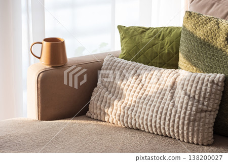 Ceramic Coffee Mug on Sofa Armrest with Textured Pillows 138200027