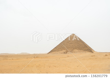 Red pyramid located in Dahshur, Egypt. The pyramid is surrounded by sandy terrain and rocky formations, showcasing ancient Egyptian architecture. 138201779