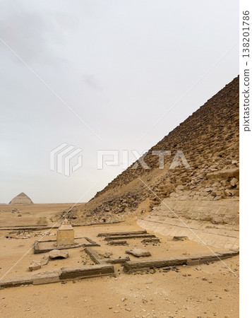 Red pyramid located in Dahshur, Egypt. The pyramid is surrounded by sandy terrain and rocky formations, showcasing ancient Egyptian architecture. 138201786
