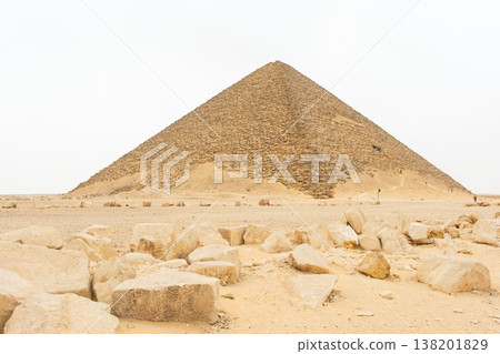 A white pyramid stands in the desert landscape of Dahshur, Egypt. The structure is partially obscured by a hazy sky, surrounded by sandy terrain. A white pyramid stands in the desert landscape of Dahshur, Egypt. The structure is partially obscured by a hazy sky, surrounded by sandy terrain. 138201829