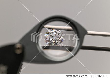 Magnifying lens focuses on a sparkling diamond held by tweezers Magnifying lens focuses on a sparkling diamond held by tweezers 138202059