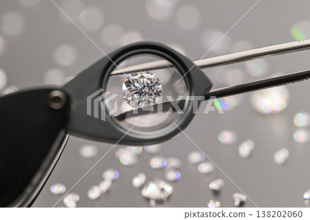 Jeweler examines flawless diamond through magnifying tool Jeweler examines flawless diamond through magnifying tool 138202060