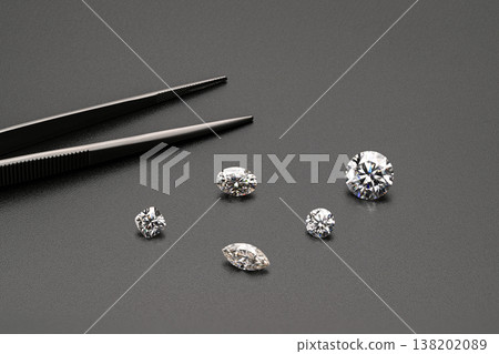 Five diamond stones arranged beside tweezers on dark background 138202089