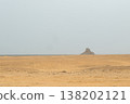 A distant view of the black pyramid in Dahshur, Egypt. The landscape features vast desert terrain with a clear sky and minimal vegetation. 138202121