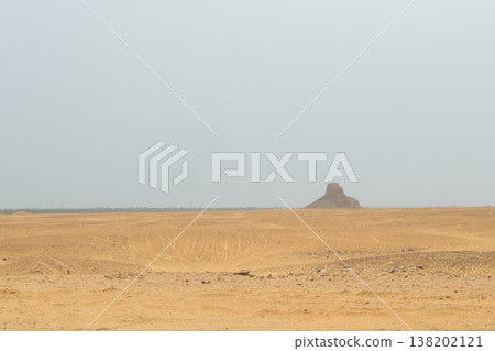 A distant view of the black pyramid in Dahshur, Egypt. The landscape features vast desert terrain with a clear sky and minimal vegetation. A distant view of the black pyramid in Dahshur, Egypt. The landscape features vast desert terrain with a clear sky and minimal vegetation. 138202121