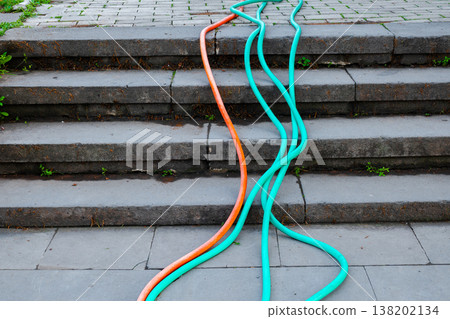 High angle view of orange and turquoise watering hoses running down weathered concrete stairs High angle view of orange and turquoise watering hoses running down weathered concrete stairs 138202134