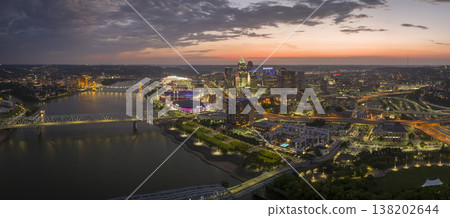 Cincinnati city, Ohio, USA with bridge highway traffic driving cars in downtown district. American city skyline with brightly illuminated high commercial buildings at night 138202644